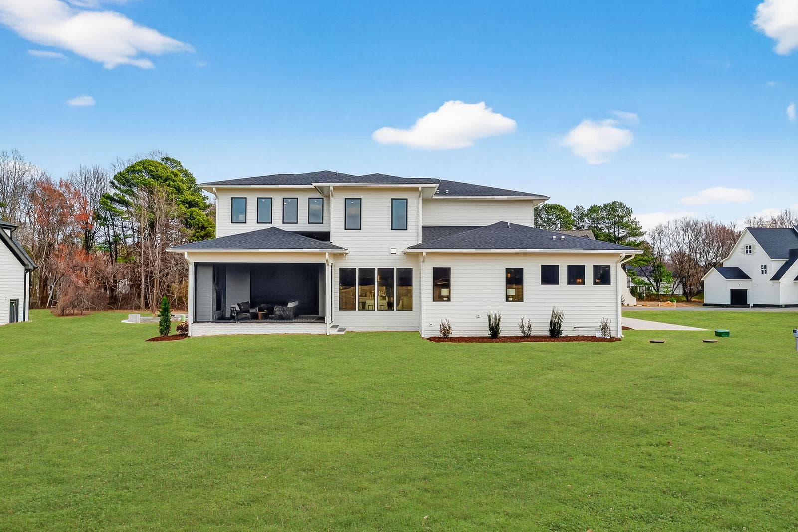 Driveway view of a modern home with expansive lawn